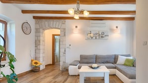 A modern living room with a stone archway, a grey sofa, a white coffee table, and a wooden ceiling.