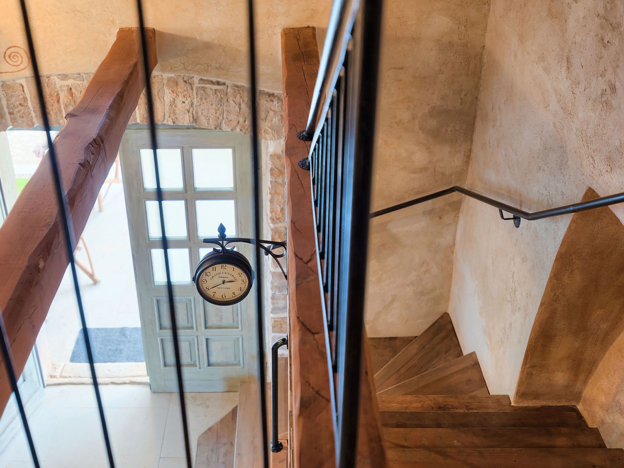 Eine Holztreppe mit Metallgeländer und einer Wanduhr.