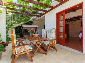 A patio with a wooden table and chairs, a covered seating area, and a red door leading to an interior space. - Ivan & Tina by Interhome (Rovinj)
