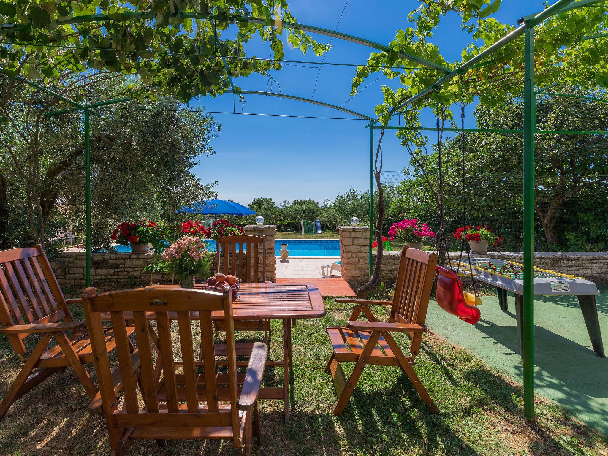 Eine Terrasse mit Holzmöbeln, einem Pool und Kübelpflanzen.