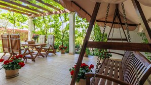 An outdoor patio with wooden furniture, including chairs and a bench, under a pergola with a swing. - Ivan & Tina by Interhome (Rovinj)