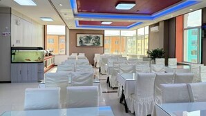 A conference room with white chairs and tables, a fish tank, and a painting on the wall. - Wudi Business Hotel (Hunchun)