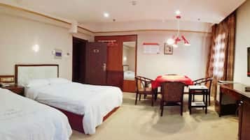 Ein Hotelzimmer mit zwei Betten, einem Schreibtisch, einem Sessel und einem Fernseher.