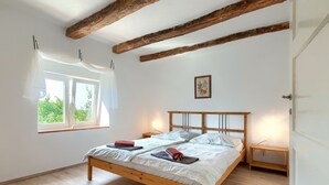 A bedroom with a wooden bed, two bedside tables, a window with curtains, and a painting on the wall. - Danijela by Interhome (Rovinj)