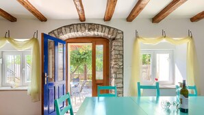 A room with a large table, chairs, a wooden ceiling, a stone archway, and windows with curtains. - Danijela by Interhome (Rovinj)