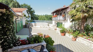 A courtyard with a table and chairs, surrounded by potted plants and flowers.