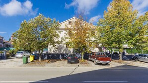 A street view with parked cars, trees, and a building with a white facade. - Apartment Alba by Interhome (Rovinj)