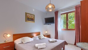 A neatly arranged bedroom with a bed, bedside lamps, a television, and a window with curtains. - Apartment Alba by Interhome (Rovinj)