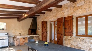 Eine rustikale Küche mit Steinwänden, Holzbalken und einem großen Tisch mit einer Bank.