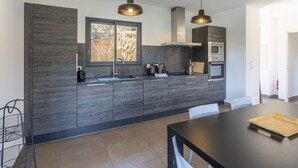 A modern kitchen with dark wood cabinetry, a large window, and pendant lighting.