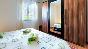 Une chambre à coucher avec un lit, une fenêtre, une armoire et un miroir.