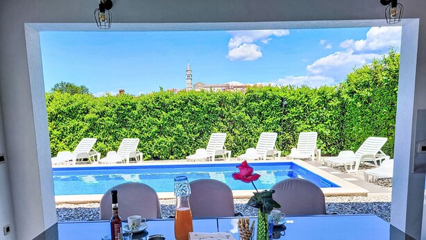 Une table avec vue sur une piscine et des chaises longues.