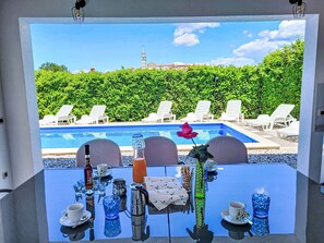A table with a view of a swimming pool and lounge chairs. - Jurican by Interhome (Poreč/Kaštelir)