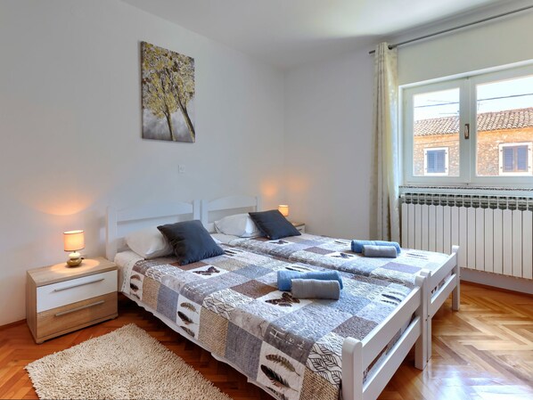 A bedroom with a bed, two bedside tables, a nightstand, a window with curtains, and a radiator. - Jurican by Interhome (Poreč/Kaštelir)