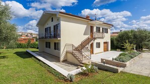 Une maison à deux étages avec un balcon, un escalier et un jardin.