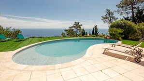 A swimming pool with a curved edge, surrounded by a tiled deck. - Ponderosa by Interhome (Théoule sur mer)
