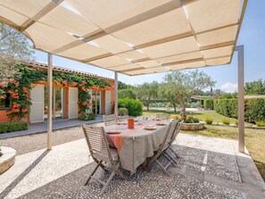 Eine Terrasse im Freien mit Esstisch, umgeben von einer Pergola mit beiger Markise.