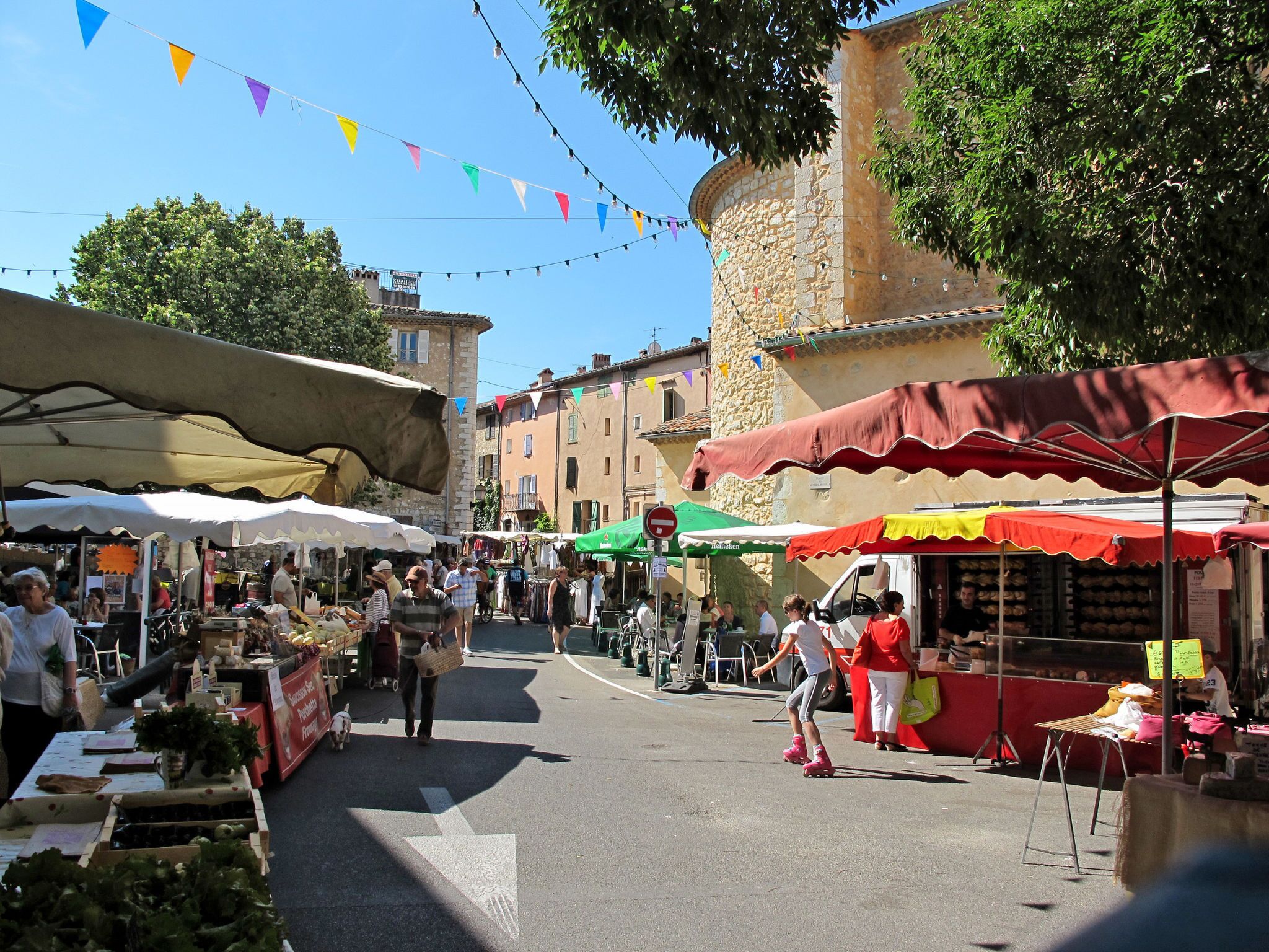 An outdoor market with stalls and people walking.