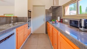 Uma cozinha moderna com armários laranja, uma pia de aço inoxidável e um forno embutido.