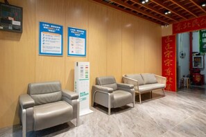 A reception area with two leather chairs, a wooden wall, and informational posters. - Aige Hotel (Shenzhen Bao'an Fanshen Subway Station) (Shenzhen)