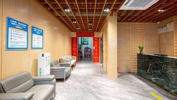 A hotel reception area with a marble floor, seating, and informational posters.