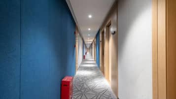A hotel corridor with blue walls, a patterned carpet, and doors on the right.