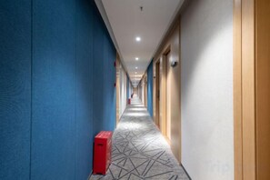 A hotel corridor with blue walls, a patterned carpet, and doors on the right. - Aige Hotel (Shenzhen Bao'an Fanshen Subway Station) (Shenzhen)
