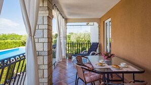 A balcony with a pool, wicker furniture, and a table with a croissant and coffee. - Apartment Čančar by Interhome (Poreč)