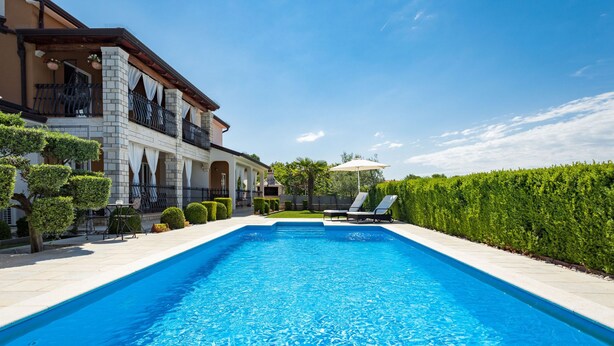A rectangular swimming pool with clear blue water, surrounded by a paved deck. - Apartment Čančar by Interhome (Poreč)