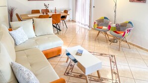 A modern living room with a sofa, coffee table, colorful chairs, a dining area with chairs and a table, and artwork on the walls. - Apartment Čančar by Interhome (Poreč)