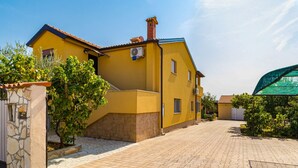 A yellow building with a tiled roof, a stone pillar, and a paved courtyard. - Apartment Dika by Interhome (Poreč)
