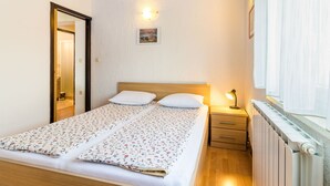 A bedroom with a wooden bed, a nightstand, a wall-mounted light, and a radiator. - Apartment Dika by Interhome (Poreč)