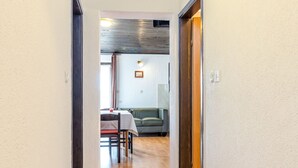 A hallway leading to a dining area with a table and chairs, a sofa, and a wooden door. - Apartment Dika by Interhome (Poreč)