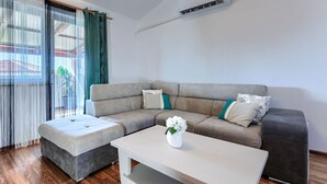 Una sala de estar moderna con un sofá modular, una mesa de centro blanca y un equipo de aire acondicionado instalado en la pared.