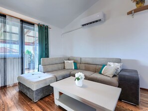 Una sala de estar moderna con un sofá modular, una mesa de centro blanca y un equipo de aire acondicionado instalado en la pared.