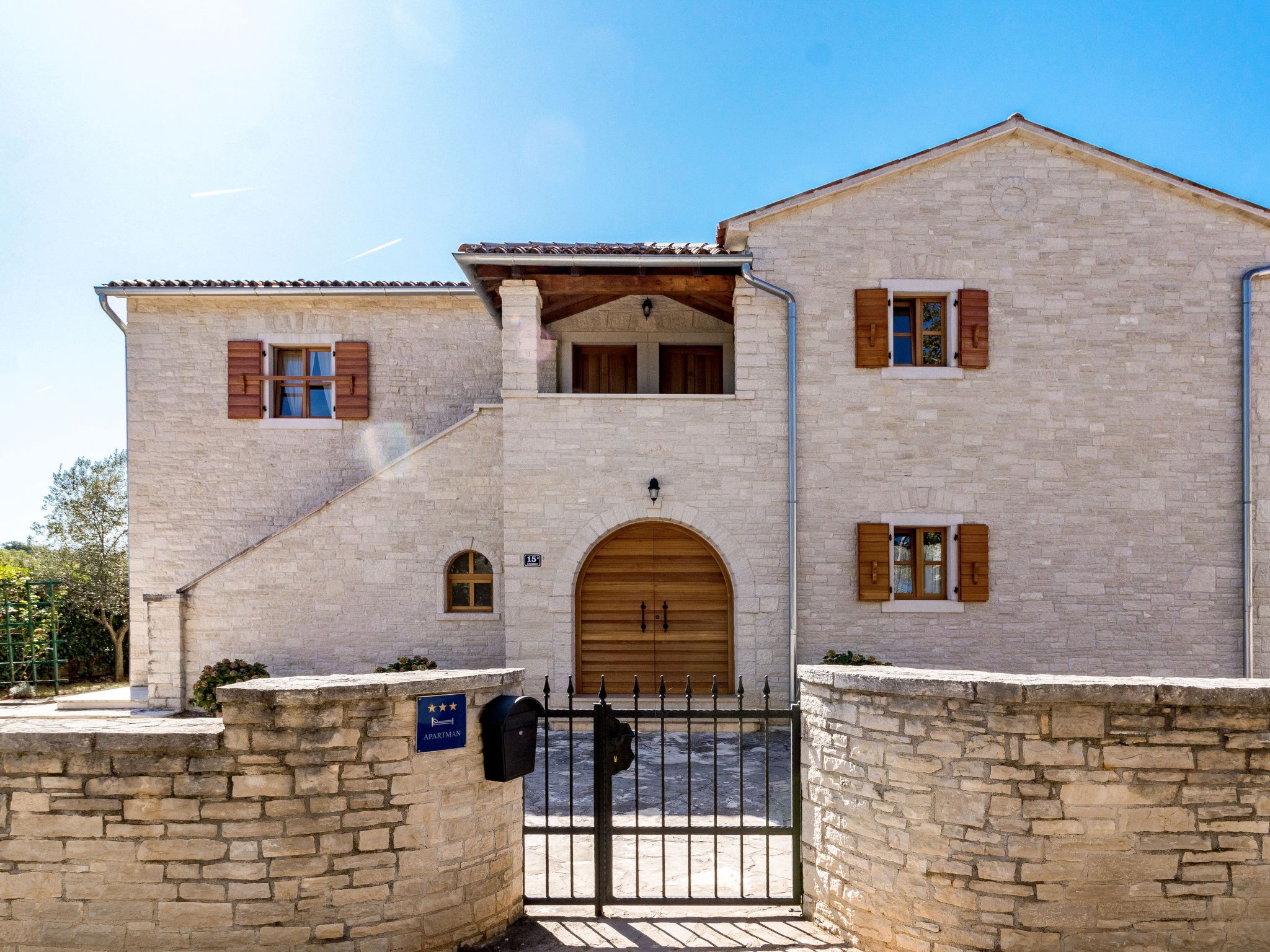 Un edificio de piedra de dos pisos con puerta y contraventanas de madera, un balcón pequeño y un letrero que indica que es un apartamento.