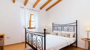 A bedroom with a metal bed frame, white bedding, a wooden floor, a small bedside table, a lamp, and a window with curtains. - Villa Sand by Interhome (Poreč)