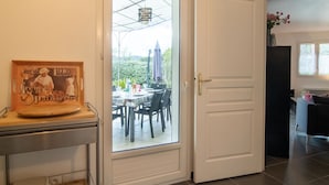 Ein Zimmer mit Essbereich, einer Tür zu einem Außenbereich und einer Wanduhr.