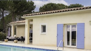 Ein Poolbereich mit Pool, Gartenmöbeln und einem Gebäude mit blauen Fensterläden.