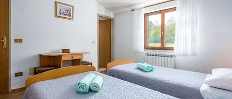 Une chambre avec deux lits, un bureau et une fenêtre avec des rideaux.