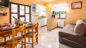 Una cocina pequeña con zona de comedor, un sofá y un televisor.