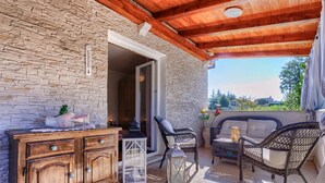 Un porche cubierto con paredes de piedra, muebles de mimbre y un armario de madera.