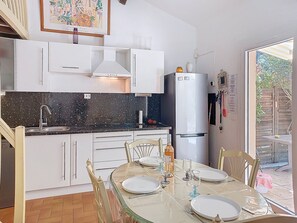 A compact kitchen with white cabinets, a black countertop, and a white refrigerator.