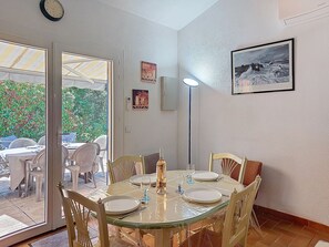A dining area with a glass table, chairs, and a clock on the wall.
