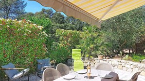 An outdoor dining area with a table set for two, surrounded by chairs, under a striped canopy. - Tiny Blue by Interhome (La Motte en Provence)