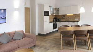 Una cocina moderna con armarios blancos, encimera de madera y comedor con mesa y sillas de madera.