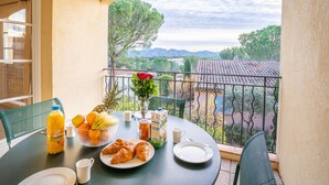 Un balcon avec une table préparée pour le petit-déjeuner, comprenant des croissants, des fruits et du jus.