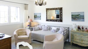 Un dormitorio con cama, dos sillas, cómoda y obras de arte en las paredes.