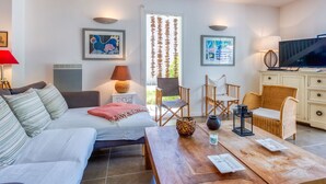 A modern living room with a sofa, a coffee table, and a TV. There are two chairs and a cabinet. - Vacation home Le Lac by Interhome (Lacanau)