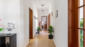A hallway with a tiled floor, wooden doors, and potted plants. - Paraíso by Interhome (Estoi)
